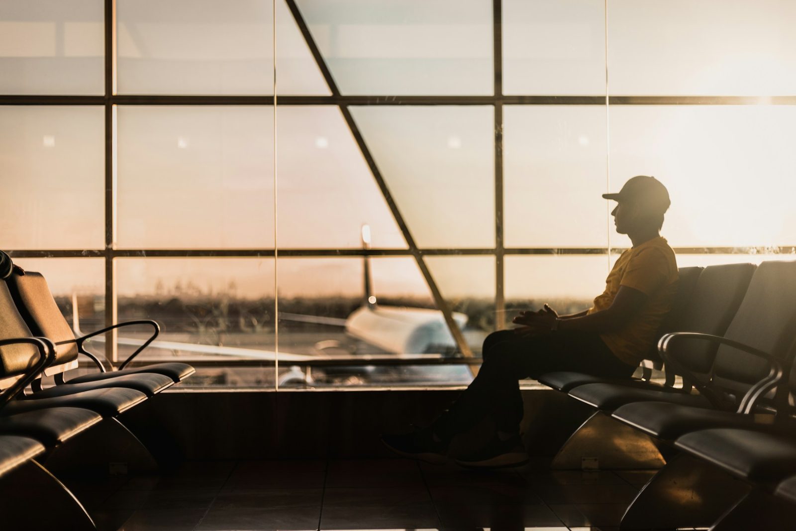 Passageiro sentado na sala de embarque de um aeroporto, ao entardecer